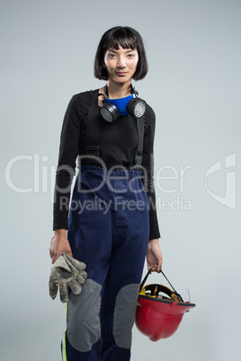 Female architect holding helmet and gloves against white background