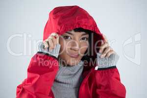 Smiling woman in hooded jacket standing against white background