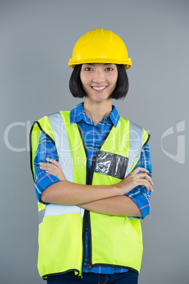 Female architect standing with arms crossed against grey background