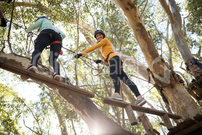 Friends enjoying zip line adventure in park