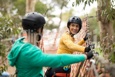 Couple interacting with each other on rope bridge