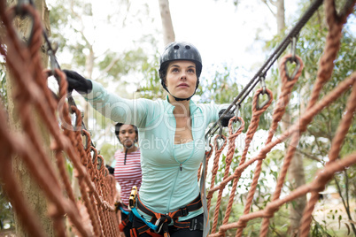 Female friends walking on rope bridge