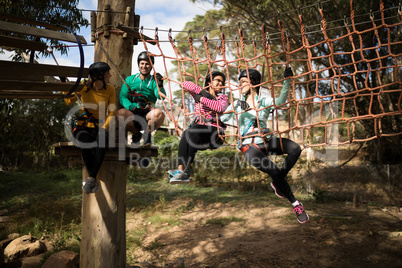 Friends relaxing on rope bridge in adventure park