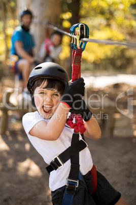 Cute boy enjoying zip line adventure on sunny day