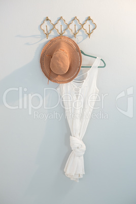 Hat and dress hanging against white wall