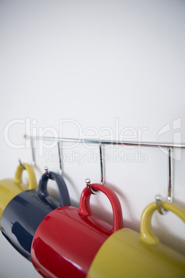 Close-up of colorful mugs hanging on hook