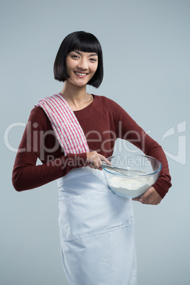 Smiling female chef mixing flour in bowl with whisk