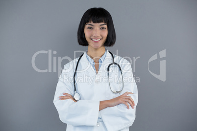 Doctor standing with arms crossed against grey background