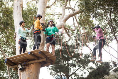 Friends enjoying zip line adventure in park