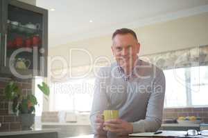 Smiling man having cup of coffee in kitchen