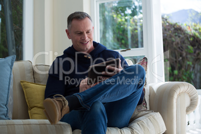 Man using digital tablet on sofa in living room