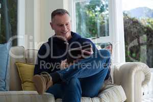 Man using digital tablet on sofa in living room