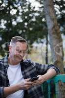 Man using mobile phone on bench in garden