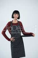 Smiling waitress holding empty tray against white background