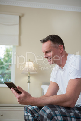 Man using digital tablet on bed in bedroom