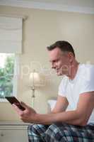Man using digital tablet on bed in bedroom