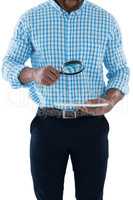 Male executive holding magnifying glass and digital tablet