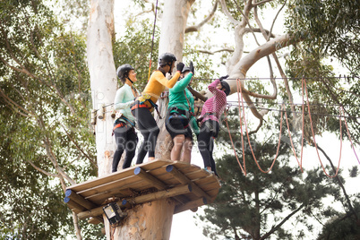 Friends enjoying zip line adventure in park