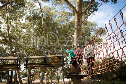 Friends having fun while walking on rope bridge