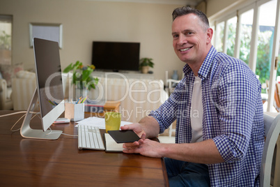 Smiling man holding mobile phone in living room