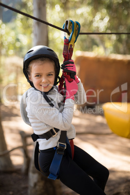 Cute girl enjoying zip line adventure on sunny day