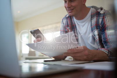 Man using mobile phone and looking at document