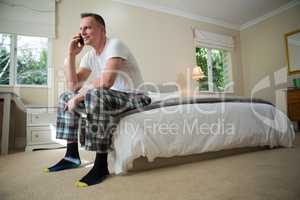 Man talking on mobile phone in bedroom