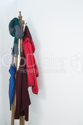 Warm clothes and umbrella on wooden stand