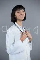 Confident doctor standing against grey background