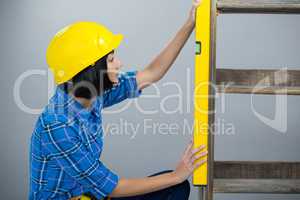 Female architect measuring plywood with engineer scale