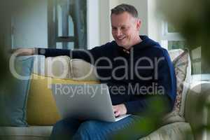 Man using laptop on sofa in living room