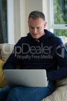 Man using laptop on sofa in living room