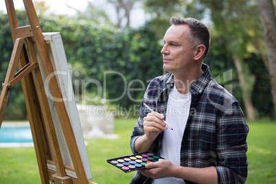 Man painting on canvas in garden