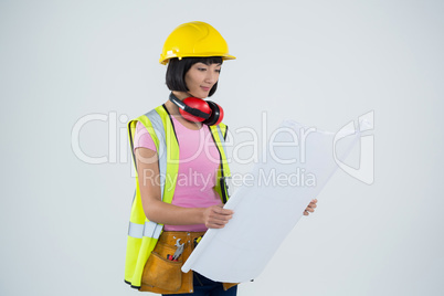 Female architect looking at blueprint against white background