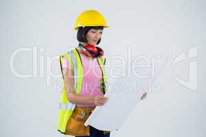 Female architect looking at blueprint against white background