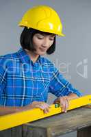 Female architect measuring plywood with engineer scale