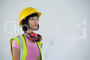 Female architect holding blueprint against white background