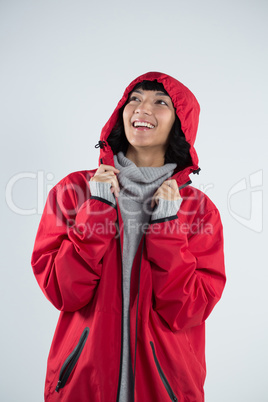 Woman in hooded jacket standing against white background