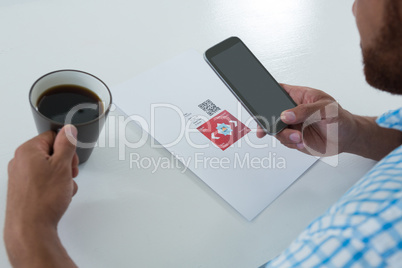 Male executive using mobile phone while having coffee