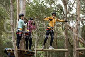 Friends enjoying zip line adventure in park