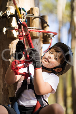 Cute boy enjoying zip line adventure on sunny day