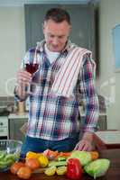 Man having glass of wine in kitchen