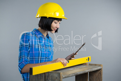 Female architect measuring plywood with engineer scale