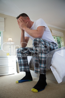 Worried man having a headache in bedroom