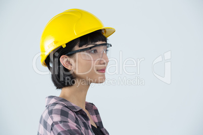 Female architect wearing hard hat and safety glasses against white background