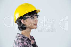 Female architect wearing hard hat and safety glasses against white background