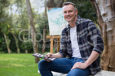 Man holding palette and brush in garden