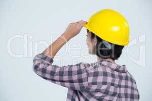 Female architect wearing hard hat against white background