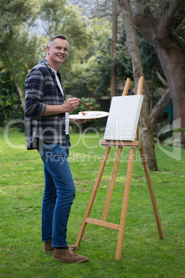 Man painting on canvas in garden