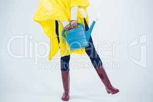Woman in yellow raincoat holding an watering can